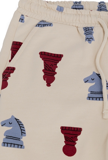 Beżowe spodnie dresowe dziecięce z motywem szachowym.