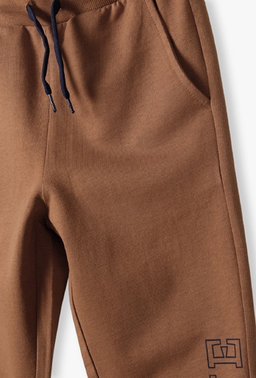 Brązowe spodnie dresowe slim fit chłopięce z napisem na nogawce