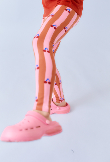 Różowo-brązowe legginsy dziewczęce z nadrukiem wisienek.