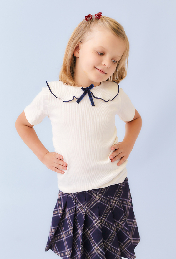 Dziewczęca koszulka ecru z ozdobnym kołnierzykiem i kokardką.