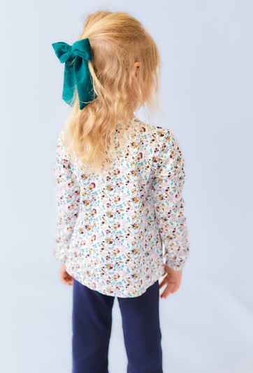 Biała bluzka dziewczęca z długim rękawem i kwiatowym nadrukiem.